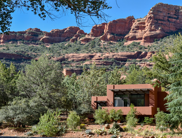 clay colored exterior of casa resort guest room with red rocks and greenery surrounding
