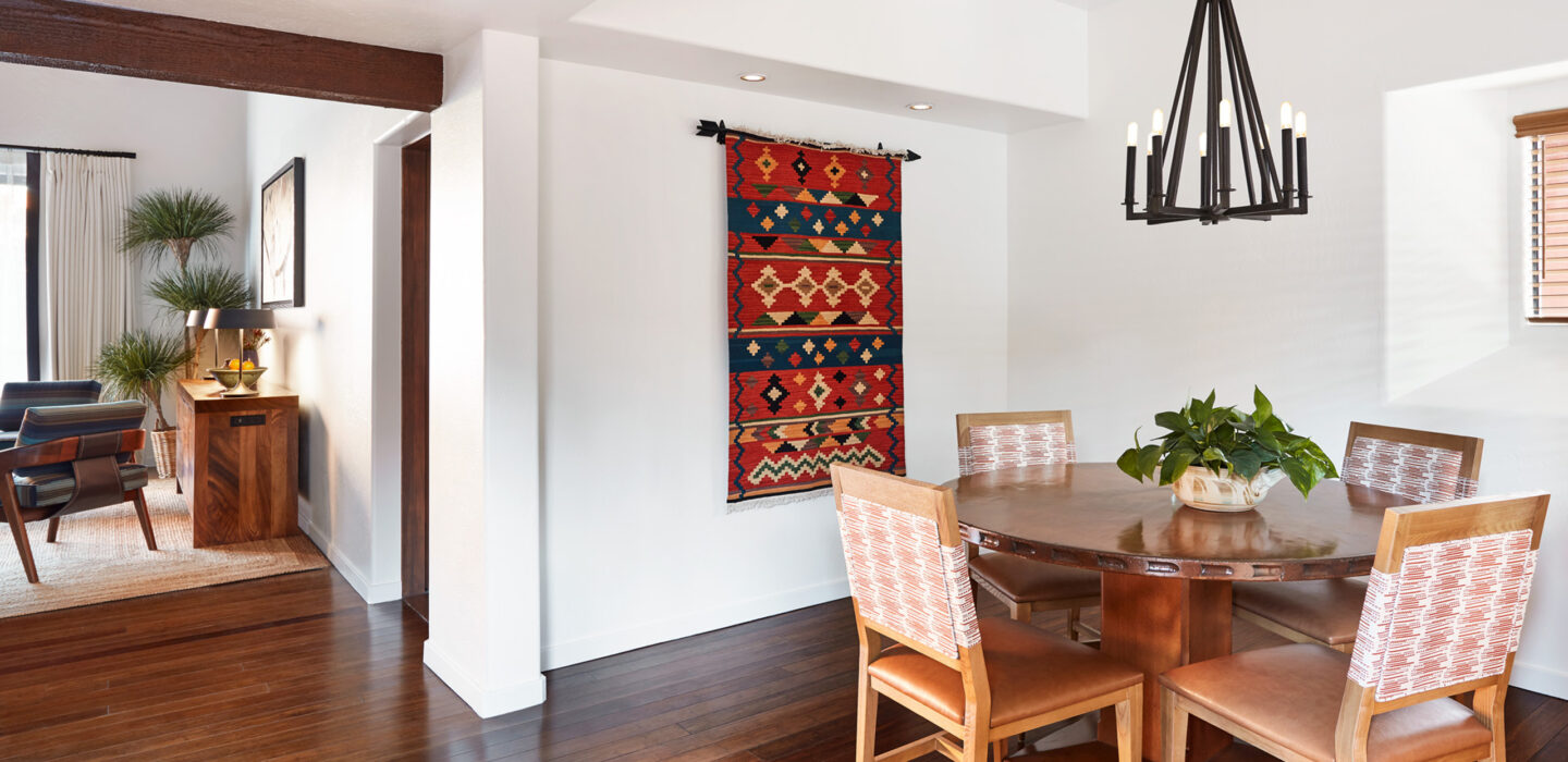 Hacienda 1 bedroom with round kitchen table and red rug hanging on wall