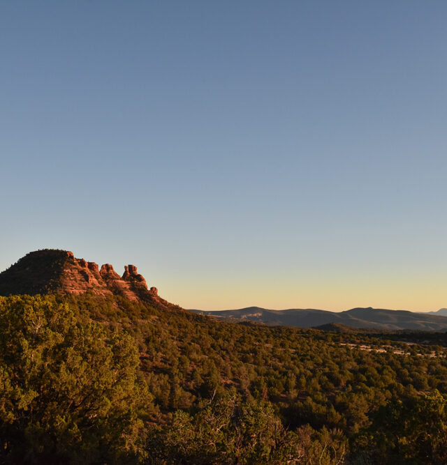 dusk scene with sun just below horizon and moon rising over mountain