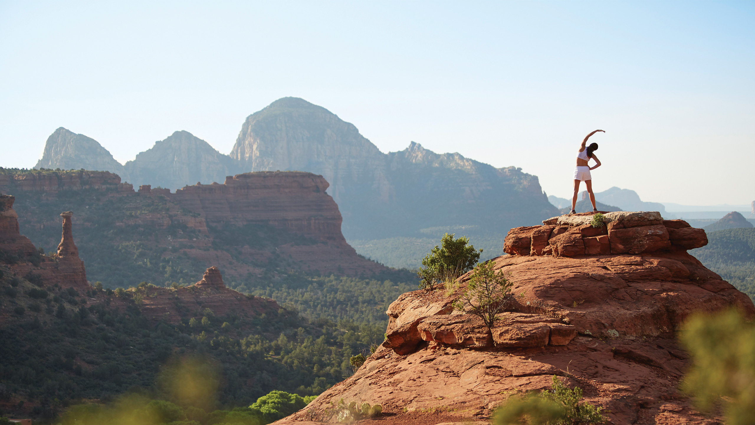 girl in white doing yoga on top of red rocks with view