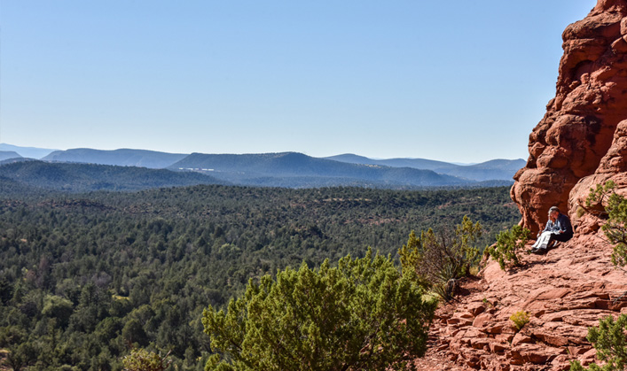 couple sitting out on overlook with blue sky