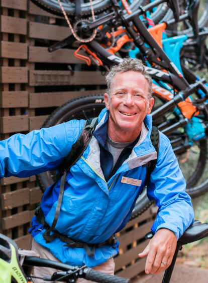 Mountain Biker with blue zip up jacket and bikes in background