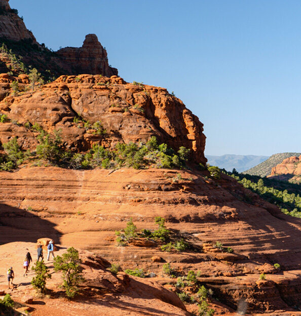 hikers on red rock path with blue sky