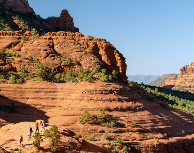 hikers on red rock path with blue sky