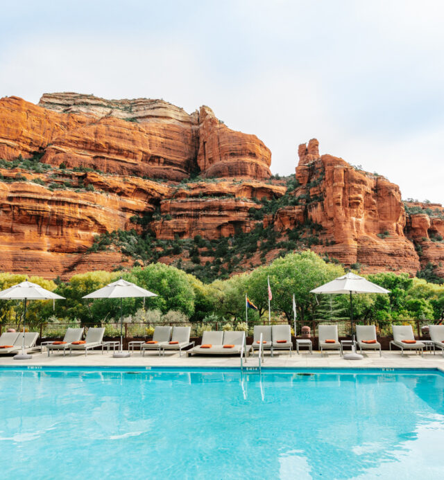 pool with umbrellas and chairs and red rock mountain in background