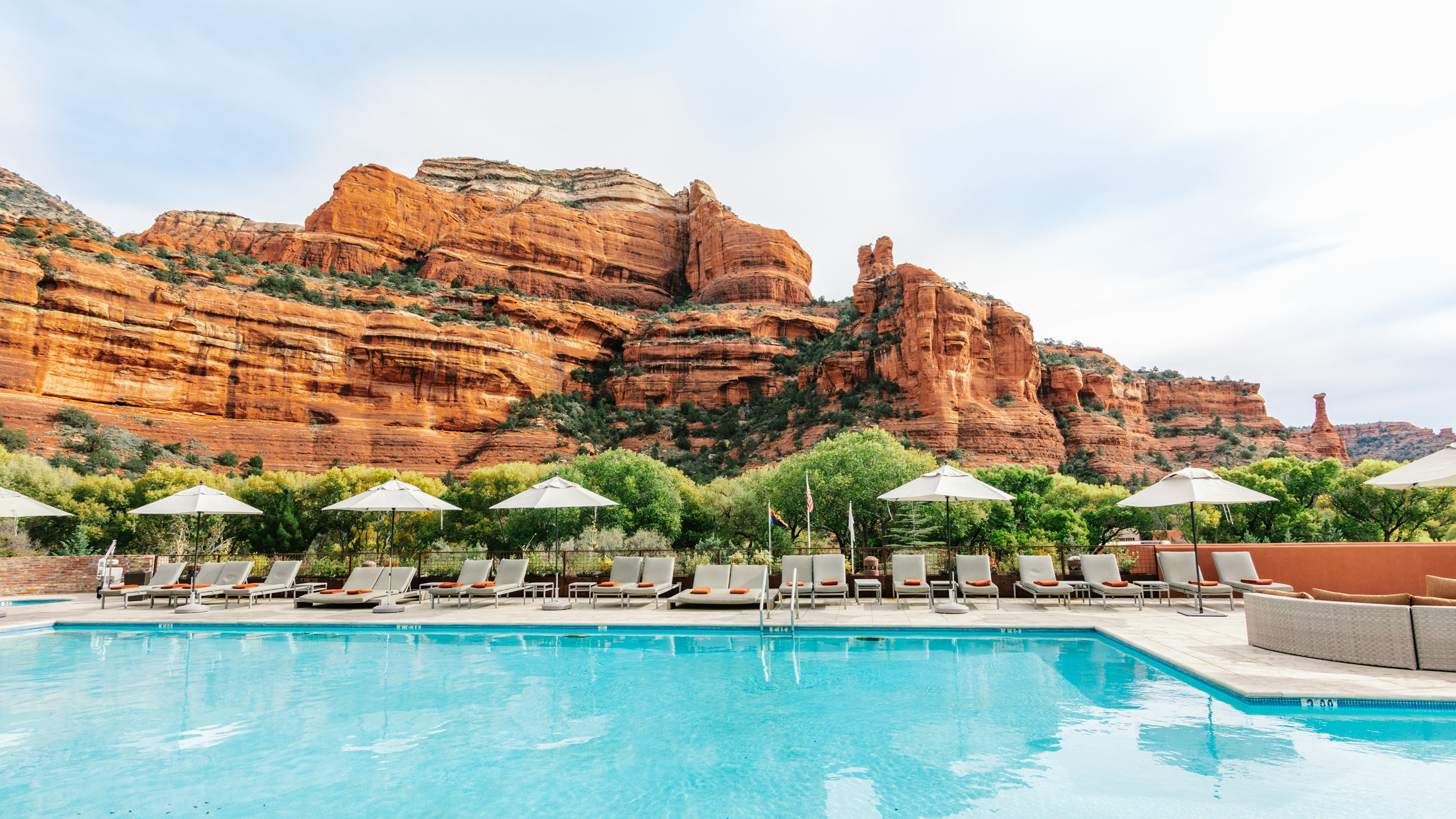 pool with umbrellas and chairs and red rock mountain in background