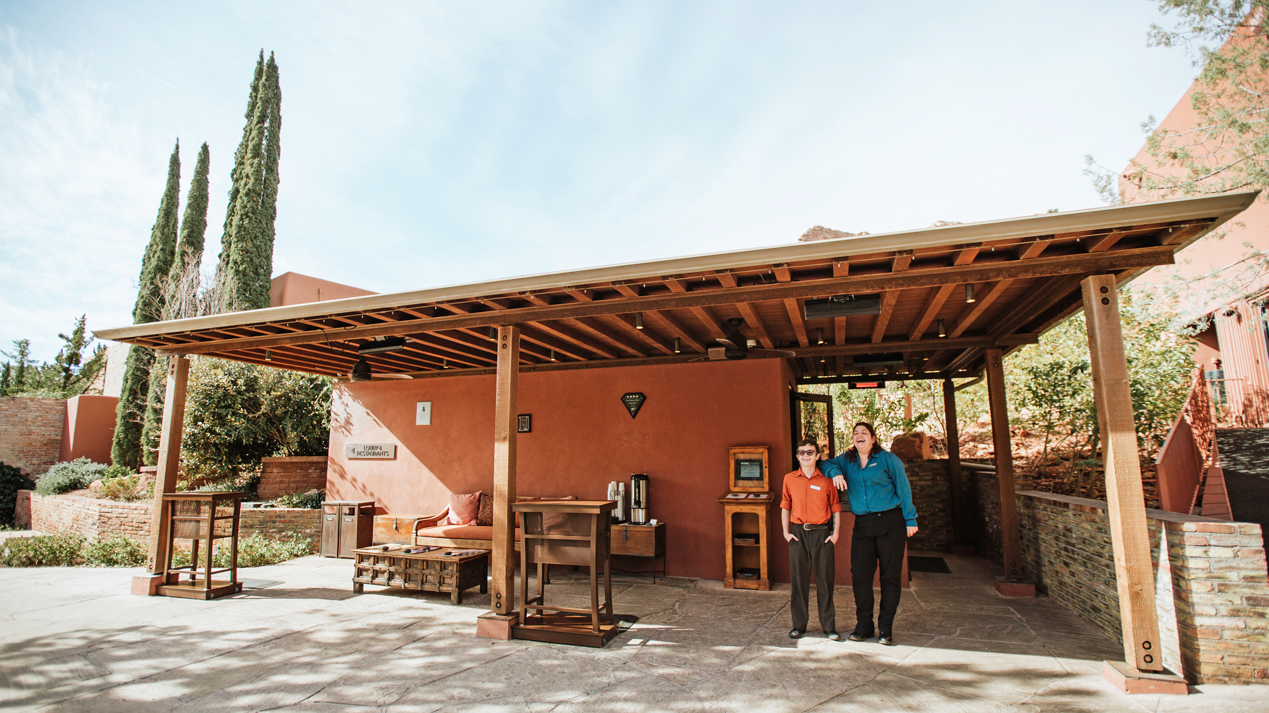 Two resort employees standing outside an adobe building laughing and smiling