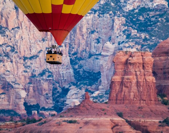 hot air balloon basket with yellow and red balloon and red rocks in background