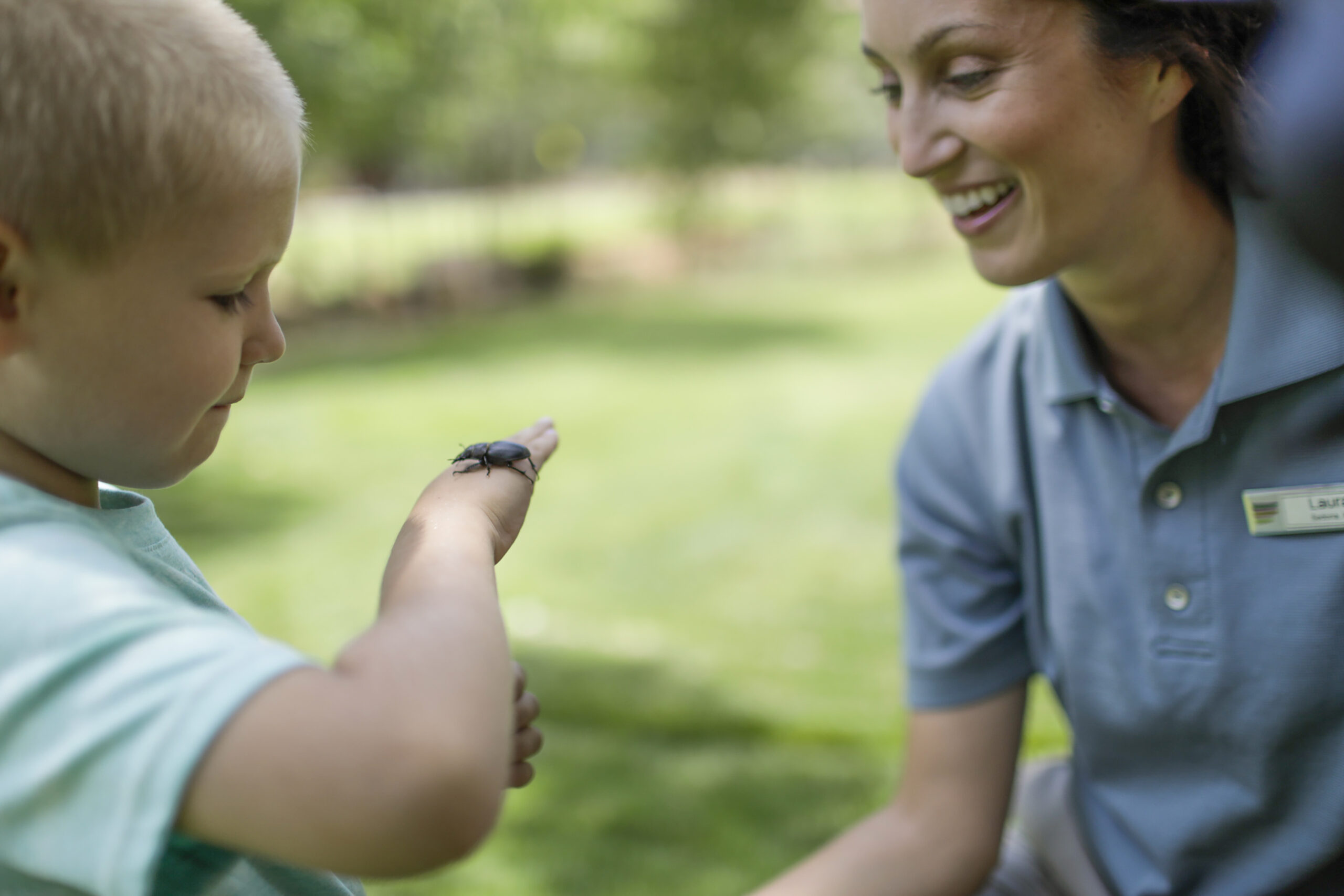woman with boy looking at bug on the boy's hand