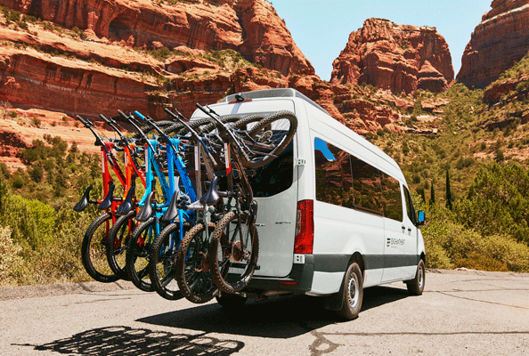 A passenger van carrying several bikes on the back