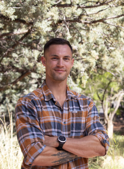 young man, brown hair, checkered shirt, posing with arms crossed