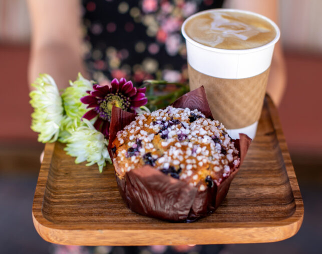wooden tray with flowers, large blueberry muffin and coffee