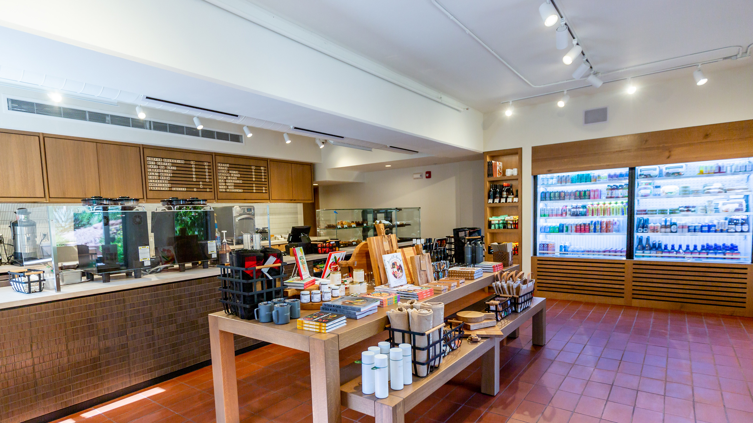 interior of coffee shop with retail table and beverage cooler filled with drinks