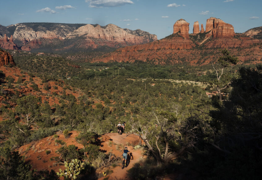 women mountain bikers on trail in Sedona with Cathedral Rock in background