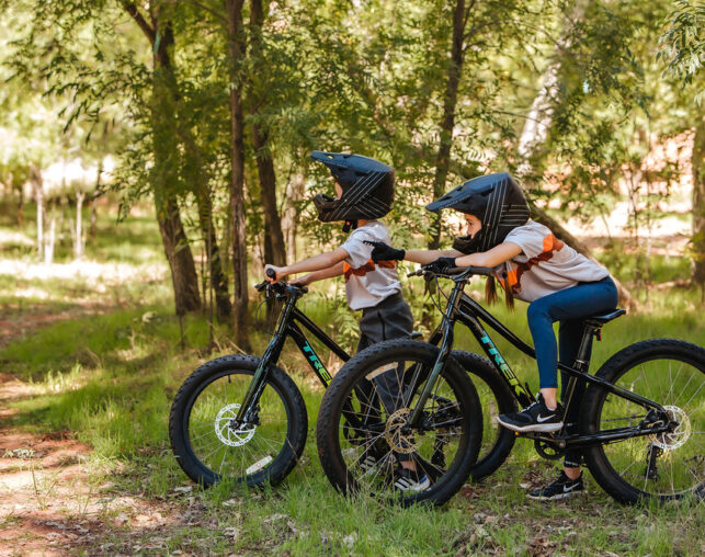 Little kids wearing black helmets on a blue mountain bike in Sedona.