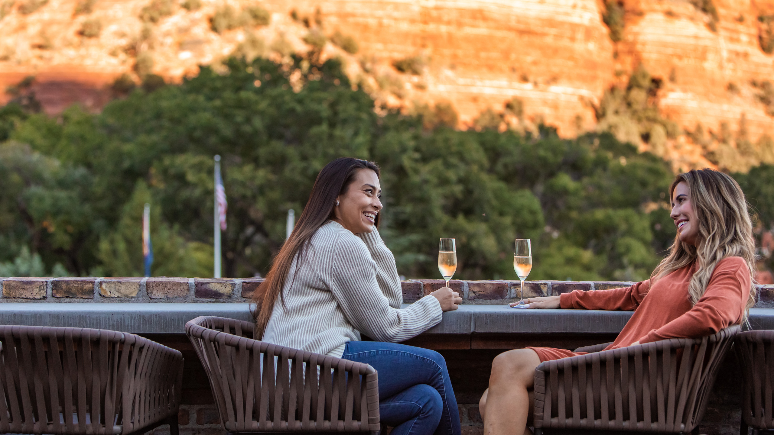 Two ladies smiling at each other as they enjoy their white wine on the patio of Che Ah Chi in Sedona, AZ