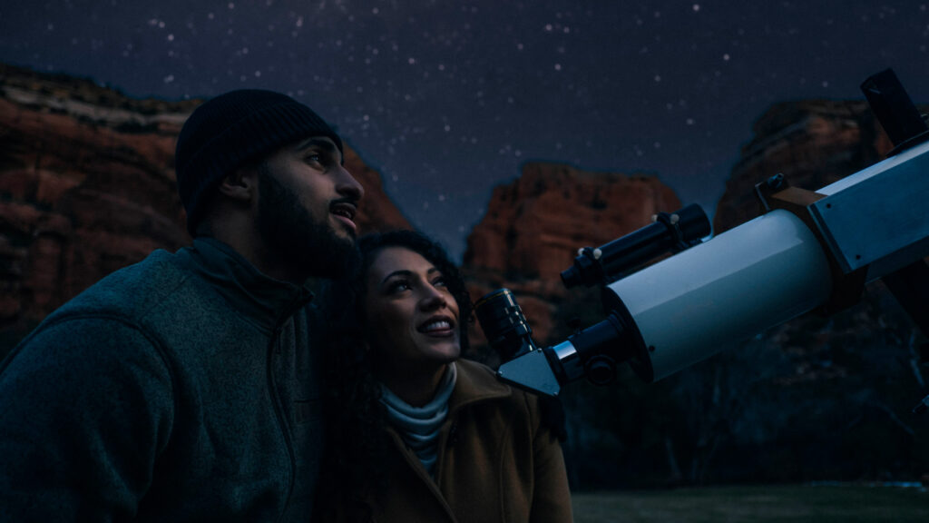 two guests looking into telescope during stargazing session in the winter at Enchantment